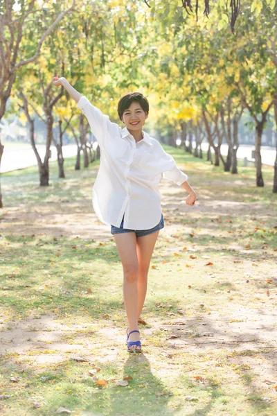 Portrait of young beautiful asian woman standing in park with re — Stock Photo, Image