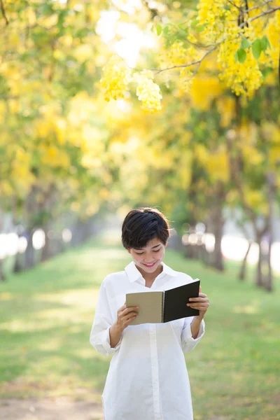 Portrait of young beautiful asian woman standing in yellow flowe — Stock Photo, Image