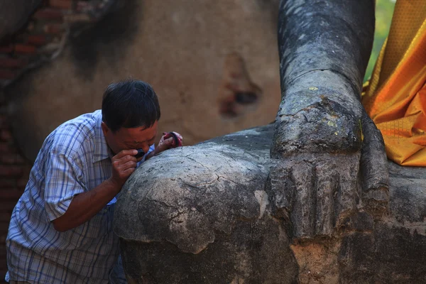 Man watching by lens magnifier on ancient buddha statue — Stock Photo, Image