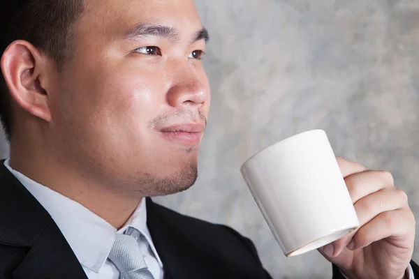 Nära håll ansikte affärsman och keramiskt kaffekopp i handen wit — Stockfoto