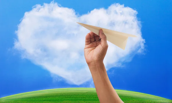 Hand preparing to throwing paper plane to mid air againt green g — Stock Photo, Image