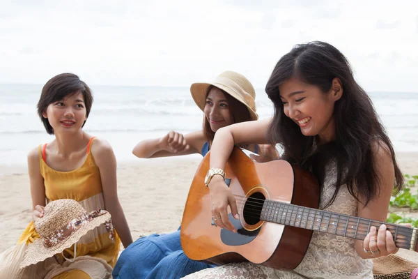 Портретная группа молодой азиатки, играющей на гитаре на морском пляже — стоковое фото