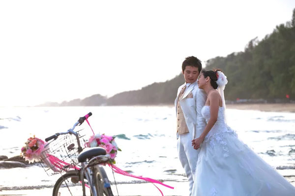 Sposo e sposa in piedi sulla spiaggia sul mare accanto alla vecchia bicicletta classica — Foto Stock