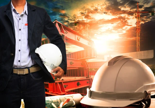 Engineer man with white safety helmet standing against working t — Stock Photo, Image
