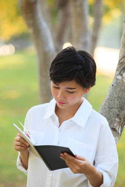 Jüngere Frau liest Buch im Park — Stockfoto