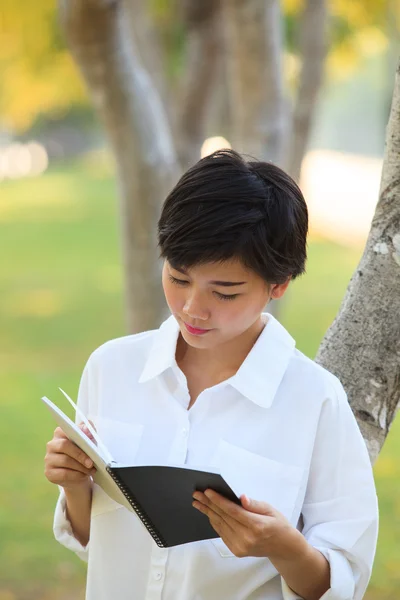 Mulher mais jovem livro de leitura no parque — Fotografia de Stock