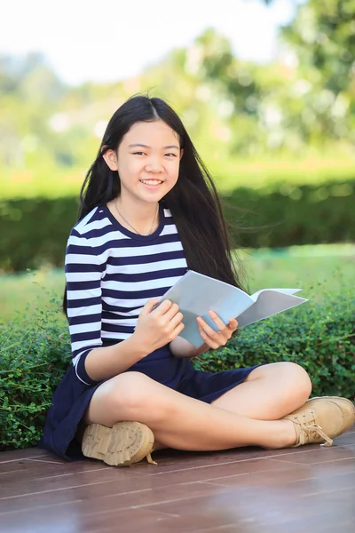 Asiatische Mädchen und Schulbuch in der Hand zahm lächelndes Gesicht mit happ — Stockfoto