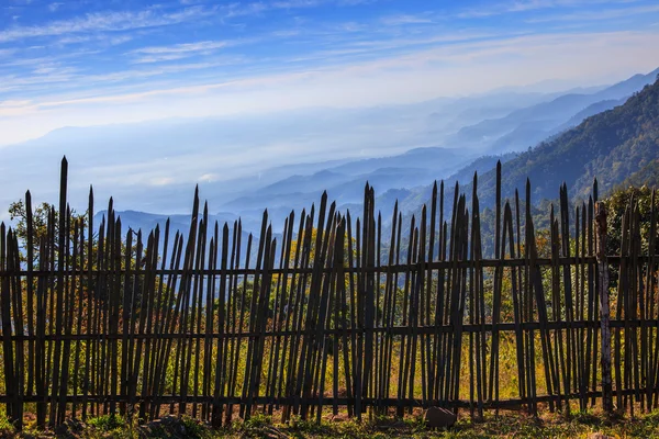 美しい自然の山の土地を持つ農村フィールドで竹フェンスします。 — ストック写真