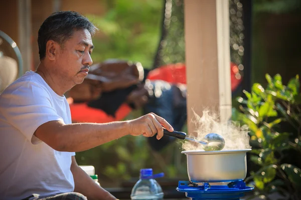 Vieil homme cuisine repas du matin dans une casserole chaude sur cuisinière à gaz lpg — Photo