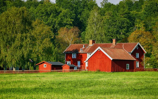 红色的旧农场的房子在农村的环境中 图库图片
