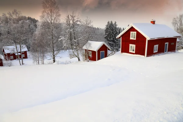 Gamla lantliga stugor draperad i en snörik vinterlandskap Royaltyfria Stockbilder