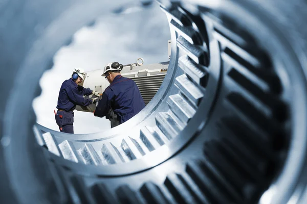 Engineers, workers seen through giant cogwheels — Stock Photo, Image