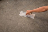 Hand mit Stahlkelle, um polierte nasse Betonoberfläche zu beenden