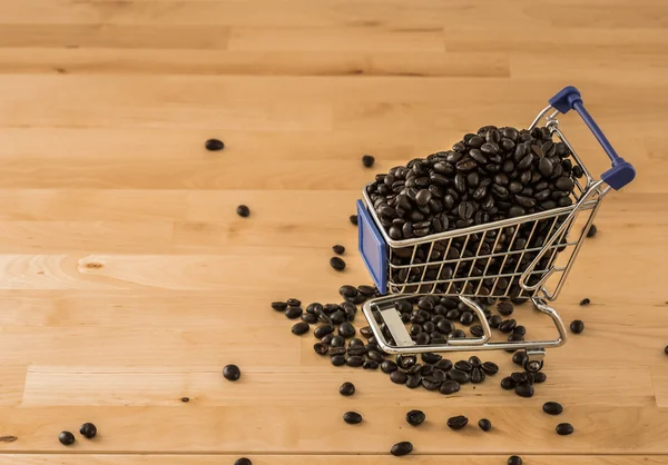 Granos de café marrón en el carro sobre fondo de madera —  Fotos de Stock