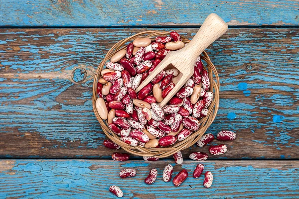 Frijoles con una cucharada en una tabla de madera . — Foto de Stock