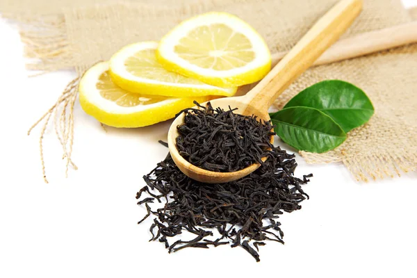 Té negro en una cuchara de madera y hojas de limón verde . — Foto de Stock