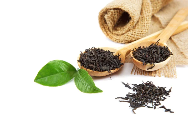 Черный чай в деревянной ложке и зеленые лимонные листья . — стоковое фото