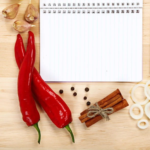 Cuaderno para recetas, verduras y especias en mesa de madera . — Foto de Stock