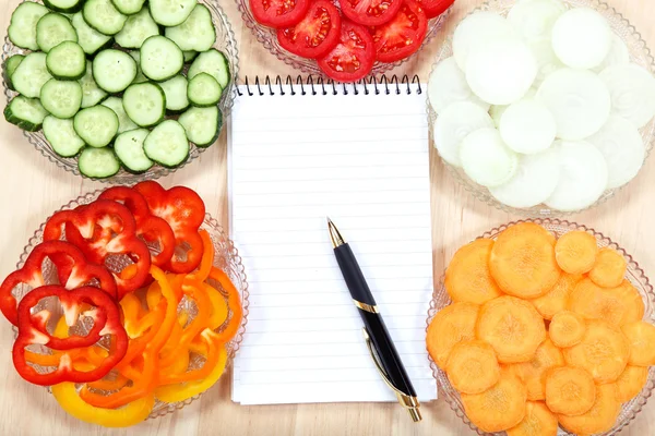 Cuaderno de recetas y verduras sobre mesa de madera . —  Fotos de Stock