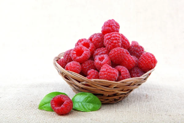 Raspberries in a basket on a homespun cloth. — Stock Photo, Image