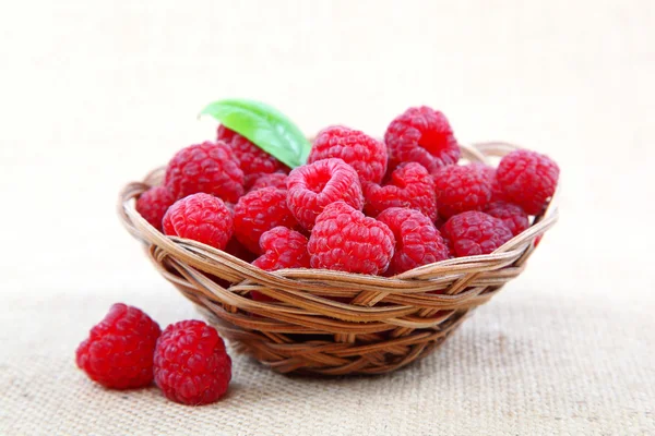 Raspberries in a basket on a homespun cloth. — Stock Photo, Image