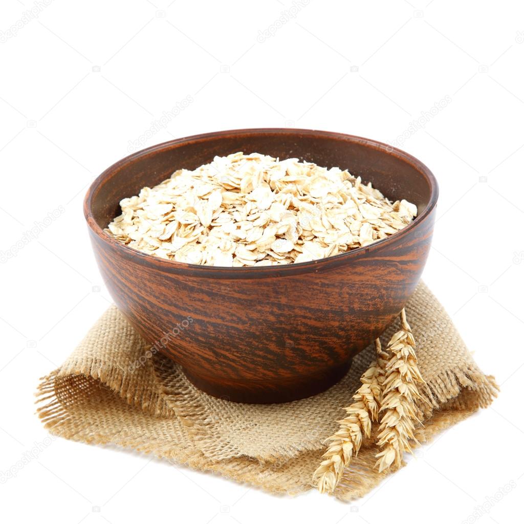 Oatmeal flakes in wooden bowl on white background. Healthy food.