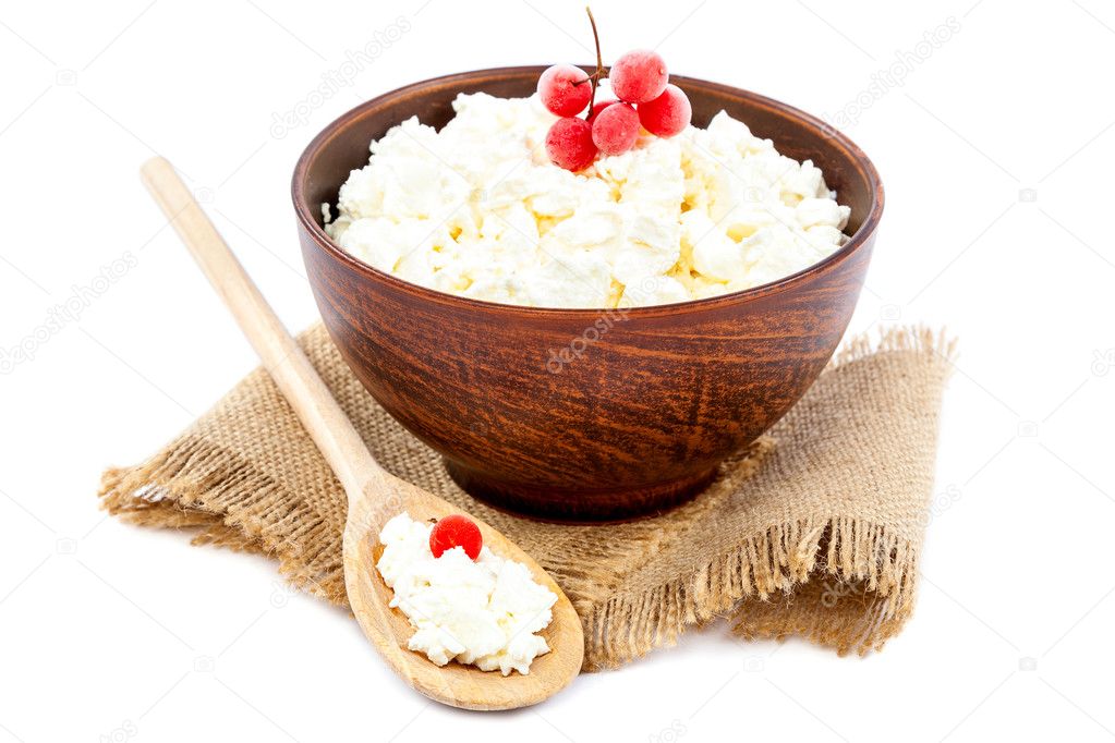 Cottage cheese in a bowl with a wooden spoon on a white backgrou