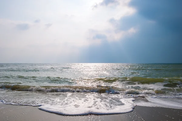 Zee golven op een zandstrand met stormy sky. — Stockfoto