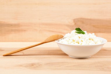 Tahta bir kaşık beyaz bir kase taze peynir.