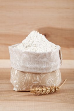 Bir tuval çanta ve kulak ahşap tahta üzerinde buğday un.