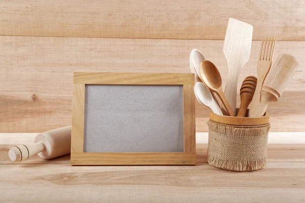 Kitchen utensils and wooden frame on a wooden board. — Stock Photo, Image