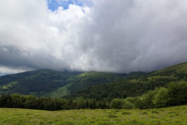 Dağın tepesine yeşil çayırlar yağmur bulutları ile.