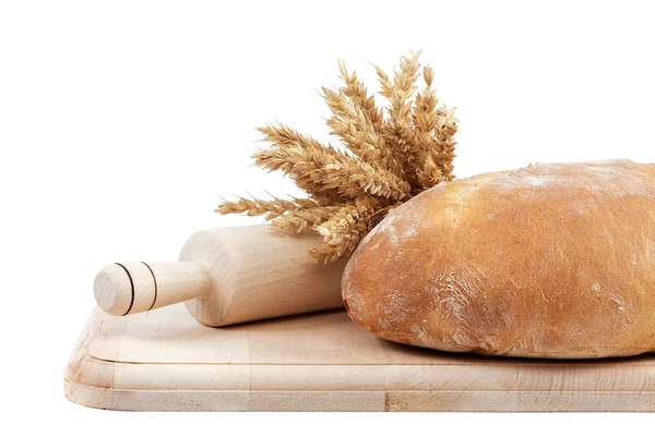 Frisches Brot und Weizenähren auf einem Holzbrett. — Stockfoto
