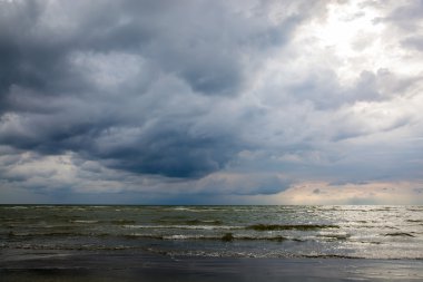 Fırtınalı gökyüzü ile kumlu bir plaj dalgalar deniz
