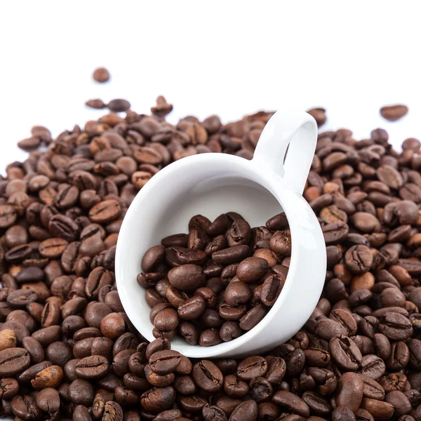 Kávová zrna a keramický pohár na bílém pozadí. — Stock fotografie