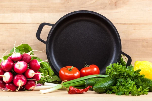 Fresh vegetables and pan on a wooden background — Stock Photo, Image