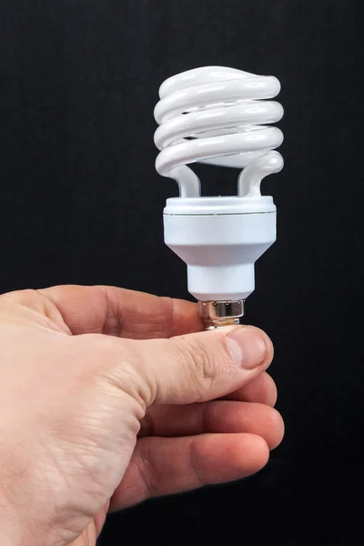 Energi spara lampa i handen på en svart bakgrund — Stockfoto