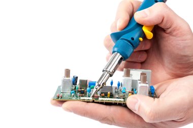 Soldering iron in hand and electric board. clipart