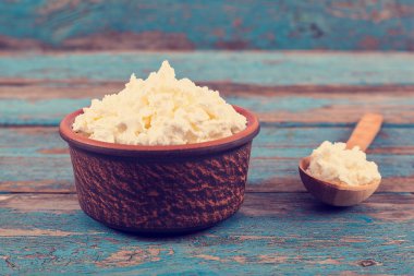 Bir seramik tabak ve tahta kaşık taze peynir.