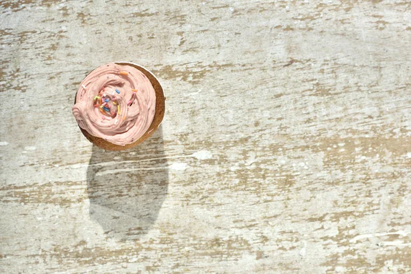 Cupcake alla fragola sul tavolo in legno in luce dura — Foto Stock