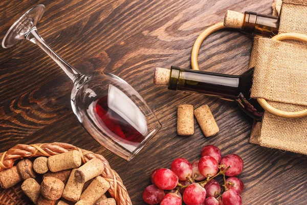 Copo com vinho, garrafas e cacho de uvas, fundo de madeira — Fotografia de Stock