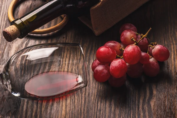 Glas mit Wein, Flasche und Trauben, Holzhintergrund — Stockfoto