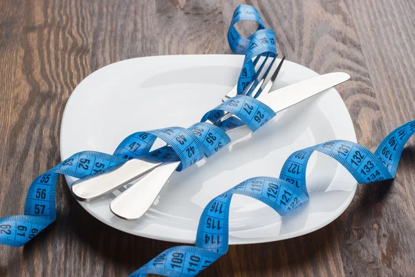 La platería, la placa y la cinta métrica, fondo de madera — Foto de Stock