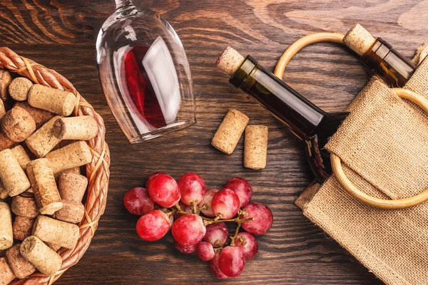 Copa con vino, botellas y racimo de uvas, fondo de madera — Foto de Stock