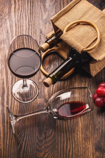 Gläser mit Wein, Flaschen und Trauben, Holzhintergrund — Stockfoto