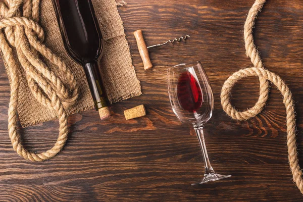 Cam şarap, şişe, tirbuşon ve çuval bezi, ahşap arka plan ile