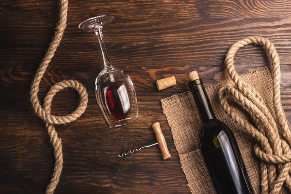 Copa con vino, botella, sacacorchos y arpillera, fondo de madera — Foto de Stock