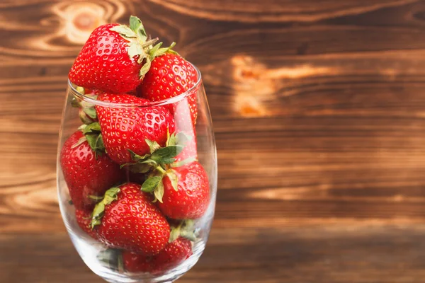 Fresas en la copa de vino sobre fondo de madera — Foto de Stock