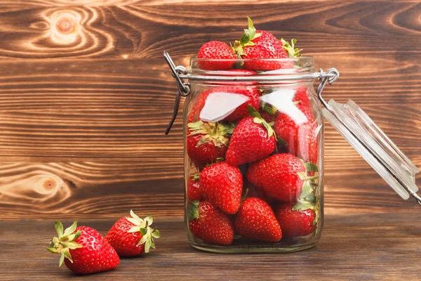 Fresas en el frasco sobre el fondo de madera — Foto de Stock