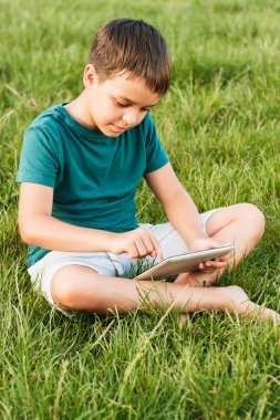 Çimenlerin üzerinde bir tablet ile genç çocuk